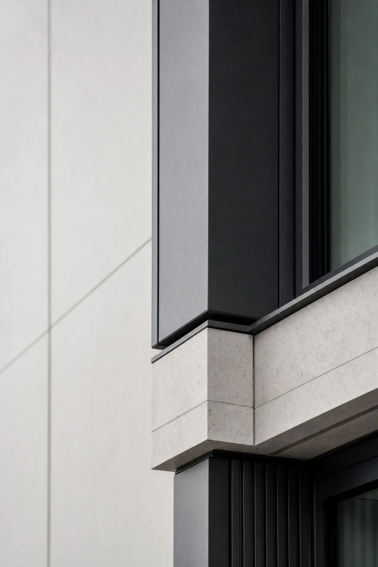 Detail of a façade interface between stone, dark cladding and glazing
